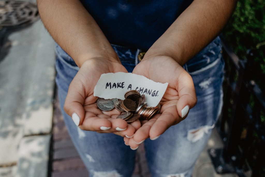 Photo of hands holding coins and sign saying "Make a Change"