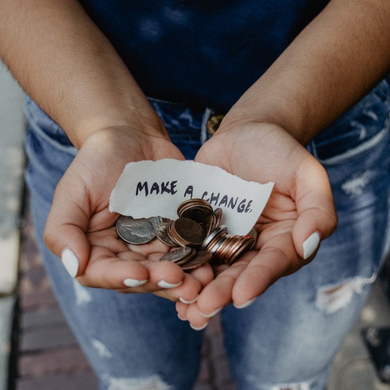 Photo of hands holding coins and sign saying "Make a Change"