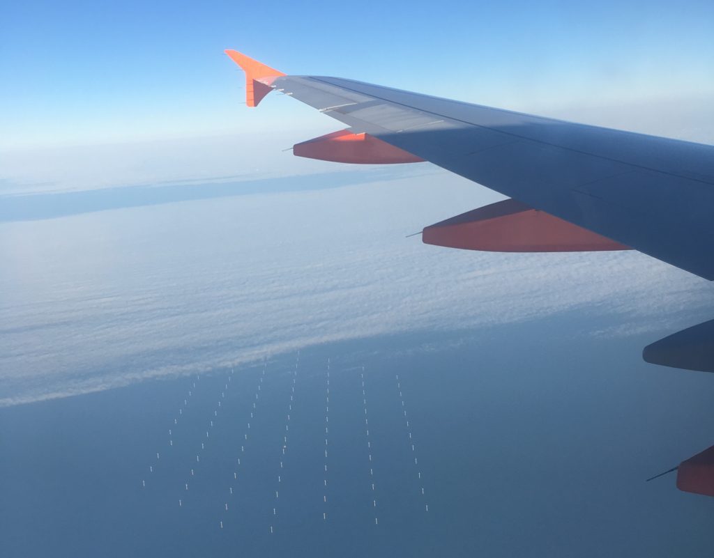Photo through plane window of wind farm