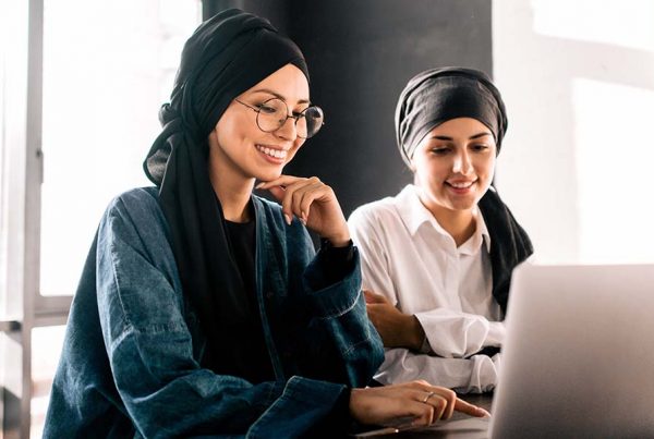 Two Women from the Middle East smile wihle looking at computer