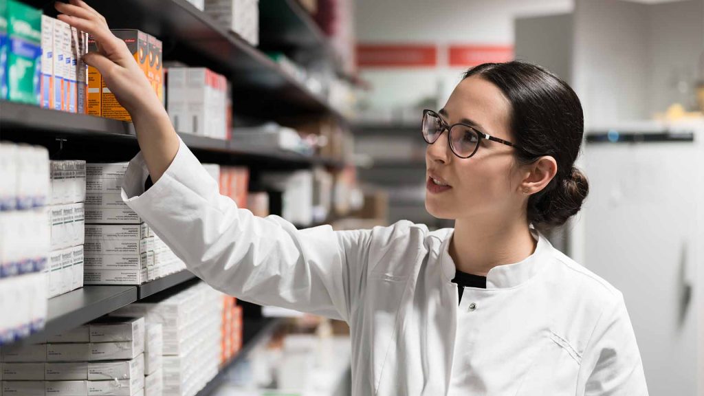 Female pharmacist picking medication off shelf