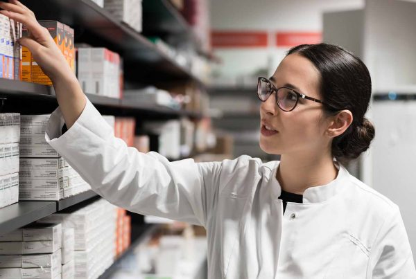 Female pharmacist picking medication off shelf