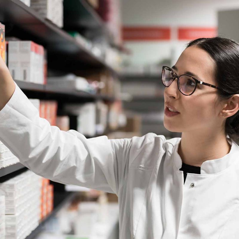Female pharmacist picking medication off shelf