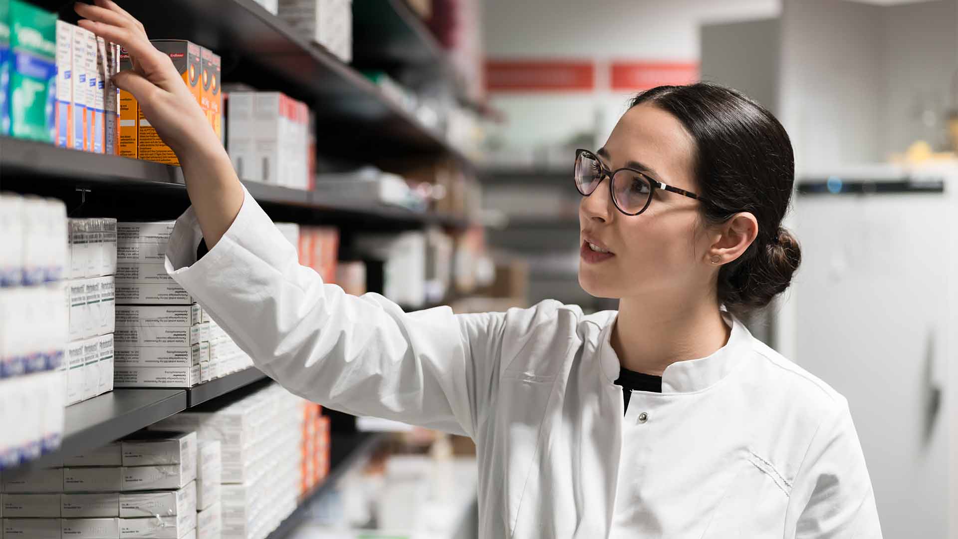 Female pharmacist picking medication off shelf