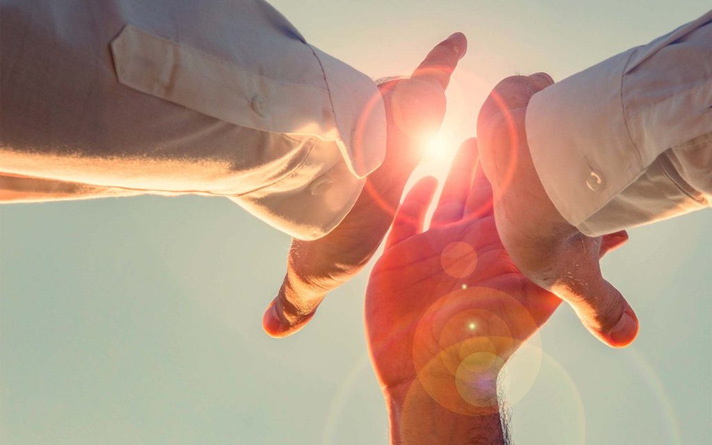 Three people high fiving with hand glowing through light