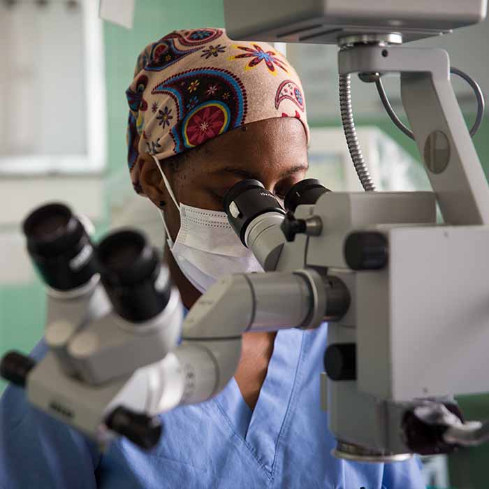 Medical professional looking through microscope