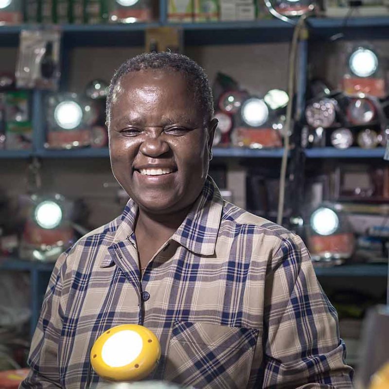 Kenyan man smiling surrounded by shining lights in shop