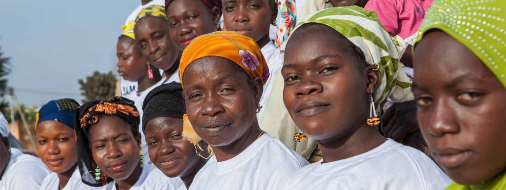 Two lines of Malian women in headscarves and white t-shirts looking at camera