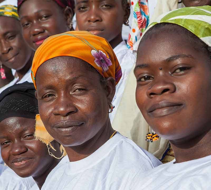 Two lines of Malian women in headscarves and white t-shirts looking at camera