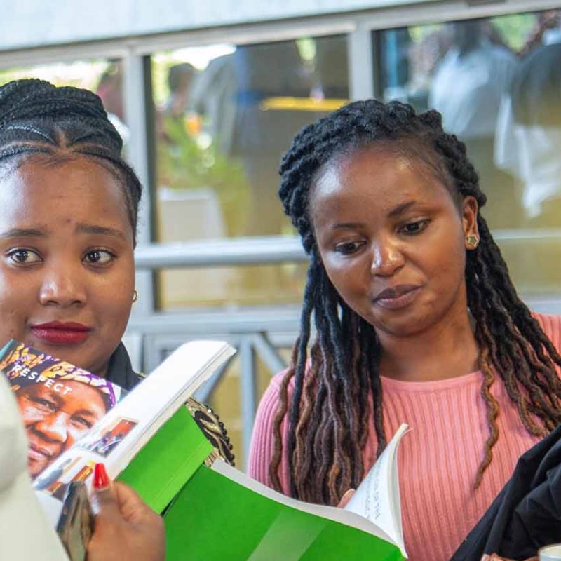 Group of women reading APHRC brochure at conference