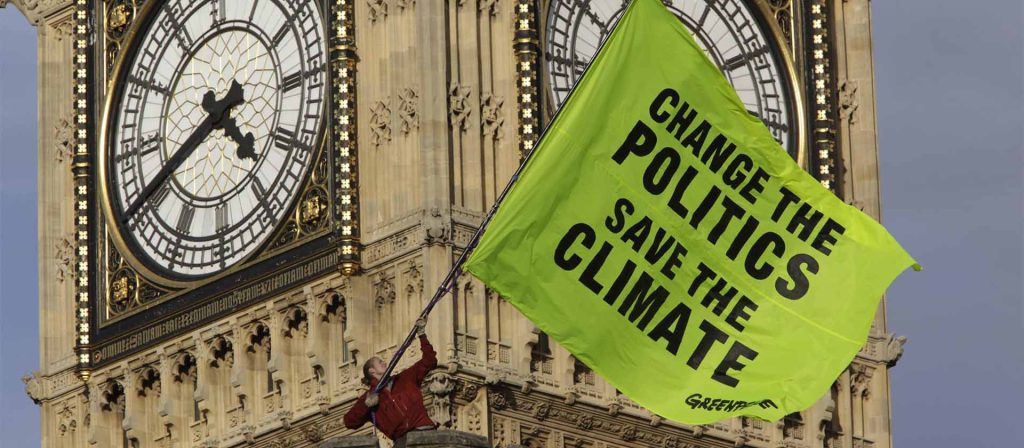 Greenpeace Activist in front of Big Ben with banner saying "Change the Politics, Save the Climate"