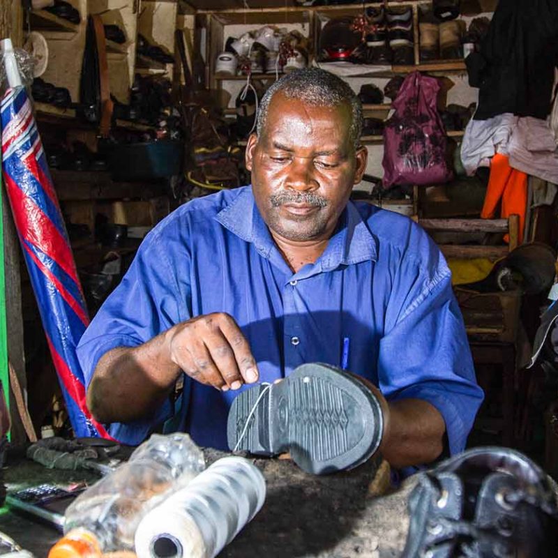Shoemaker repairing shoe in his store