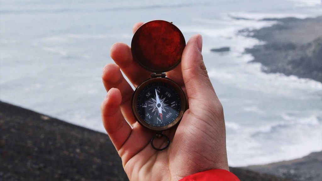 Man with a compass overlooking the sea