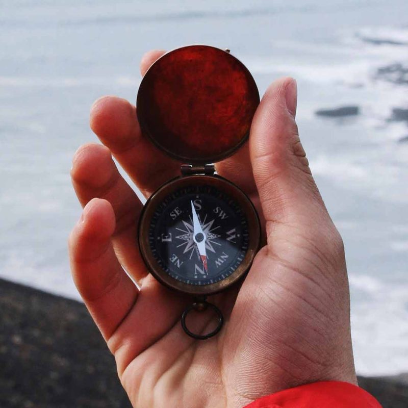 Man with a compass overlooking the sea