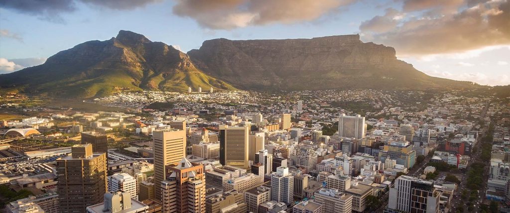 An aerial view of Cape Town central business district in late afternoon as the sun is setting, showing Table Mountain.