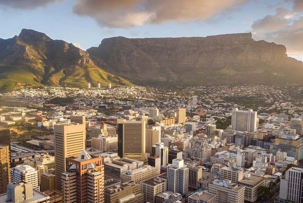 An aerial view of Cape Town central business district in late afternoon as the sun is setting, showing Table Mountain.