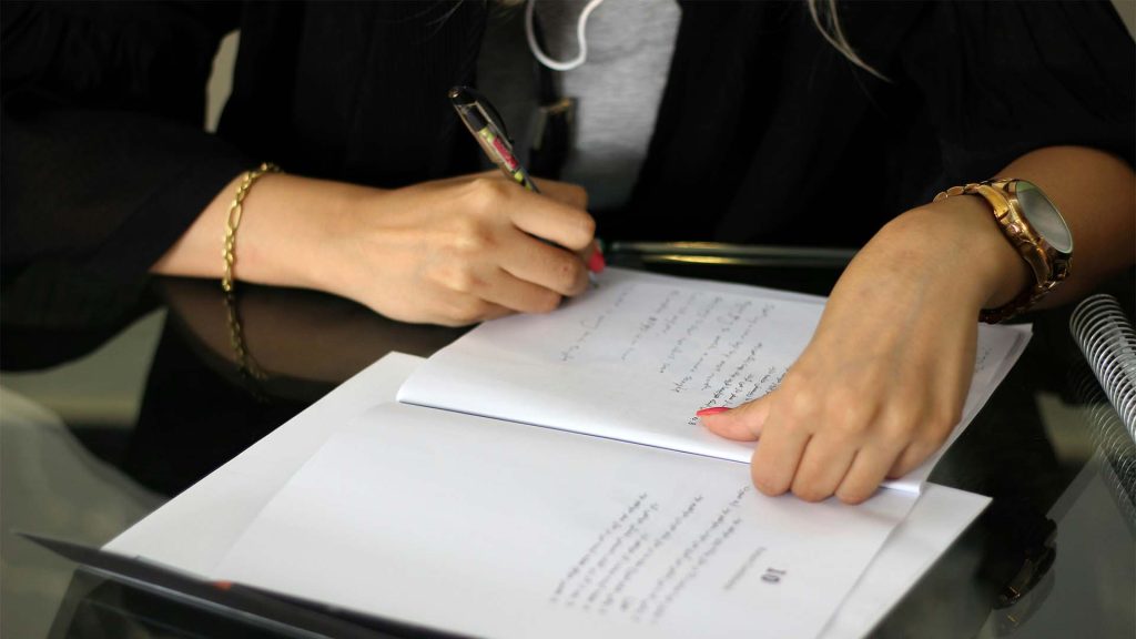 Person writing on paper at desk