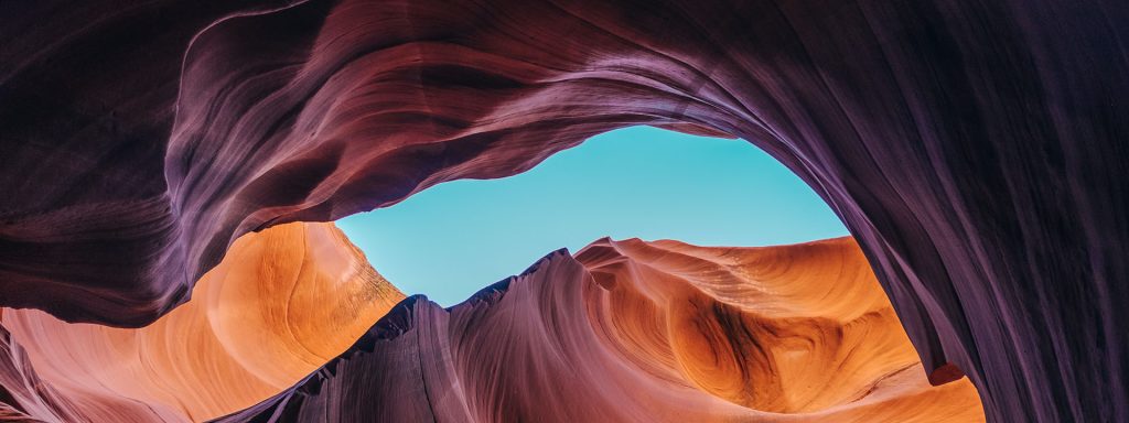 Looking up at a swirling rock formation, with the blue sky visible in the middle