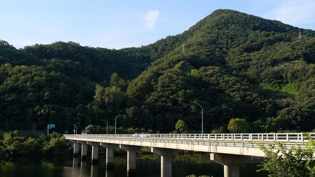a bridge over a body of water with a mountain in the background in Daejeon, South Korea