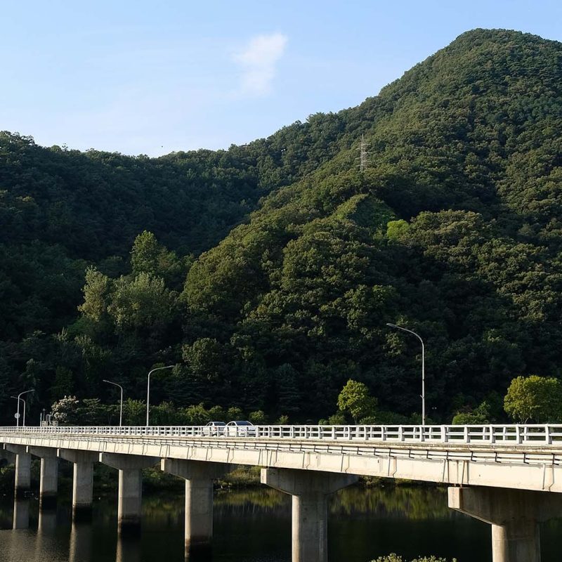 a bridge over a body of water with a mountain in the background in Daejeon, South Korea