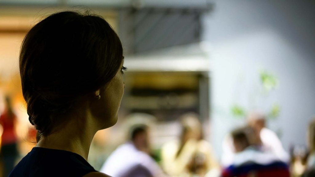 A woman looks around an office full of people