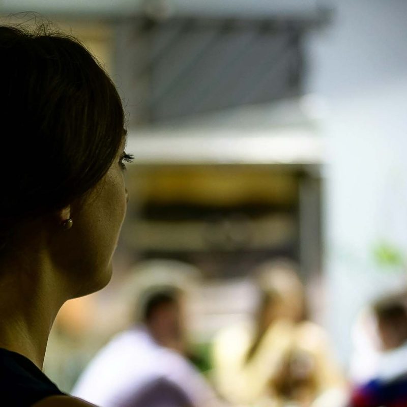 A woman looks around an office full of people