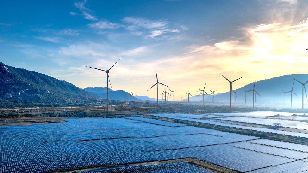 Landscape featuring solar panels and wind turbines at sunrise