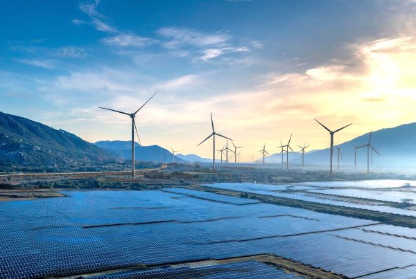 Landscape featuring solar panels and wind turbines at sunrise