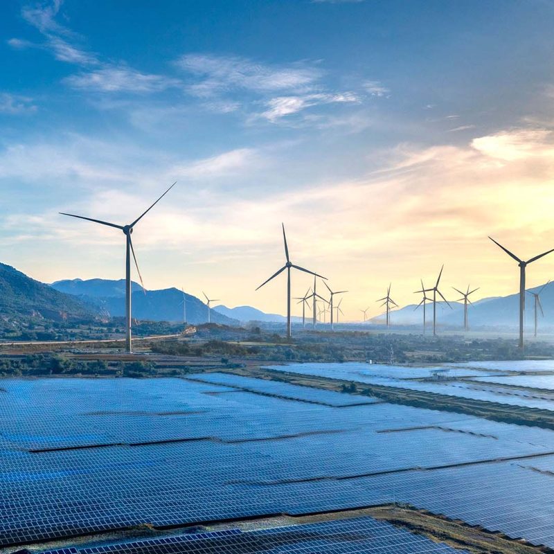 Landscape featuring solar panels and wind turbines at sunrise