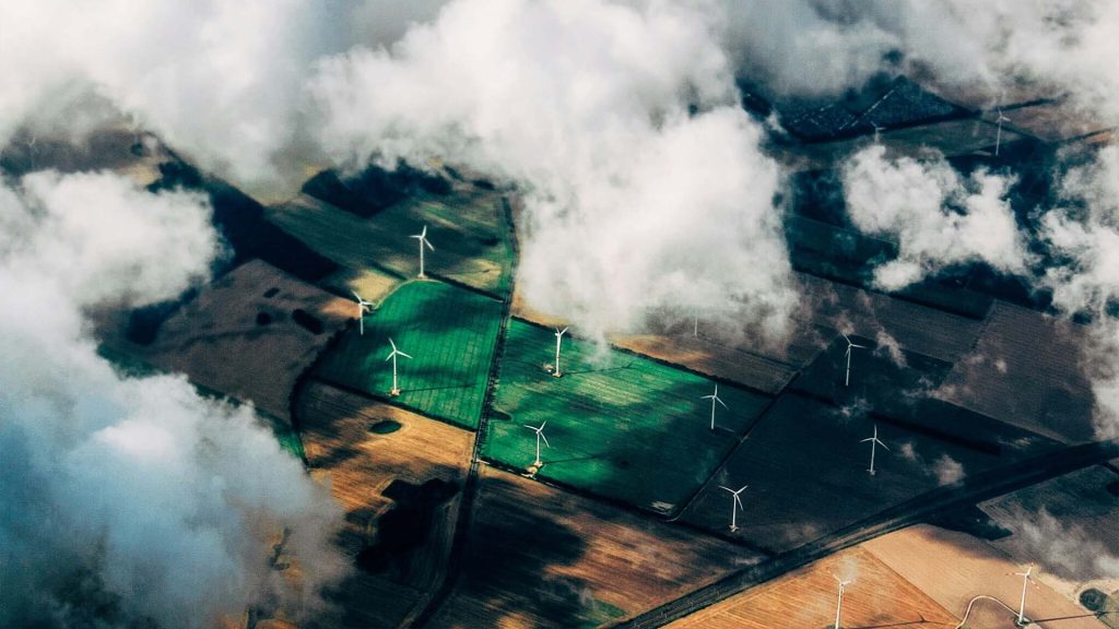 Aerial photo of clouds casting shadow on fields with wind turbines