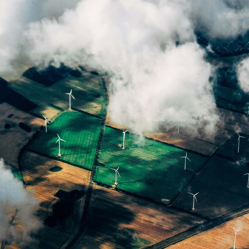 Aerial photo of clouds casting shadow on fields with wind turbines